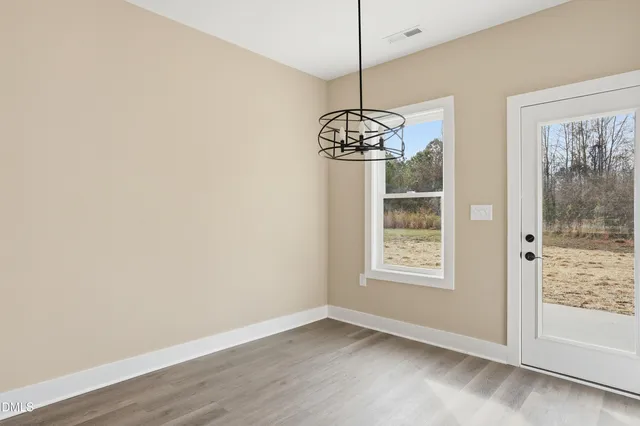 a view of an empty room with window and chandelier