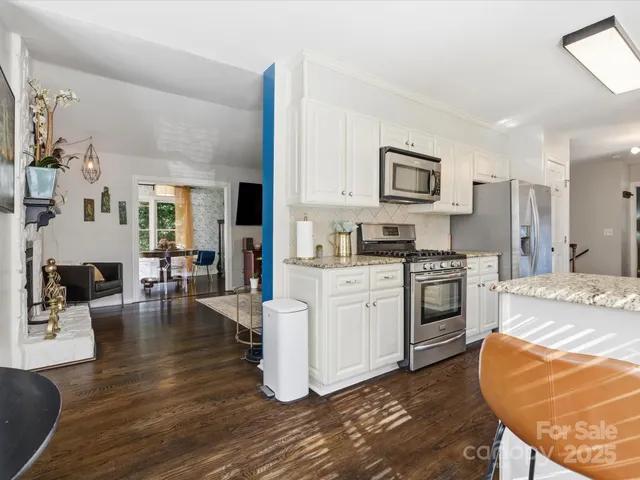 a kitchen with granite countertop a stove a sink dishwasher and a refrigerator with white cabinets