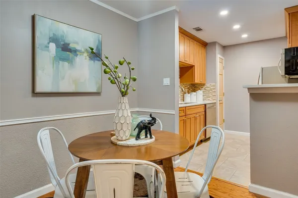 a view of a dining room with furniture one side kitchen view and wooden floor