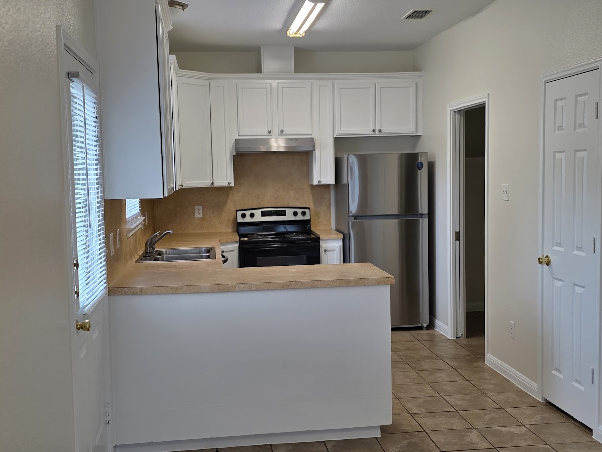 3308 Elija Street, Unit B Austin, TX 78745 - Photo 3 of 20 Kitchen featuring white cabinets, freestanding refrigerator, light countertops, black range with electric stovetop, and a peninsula