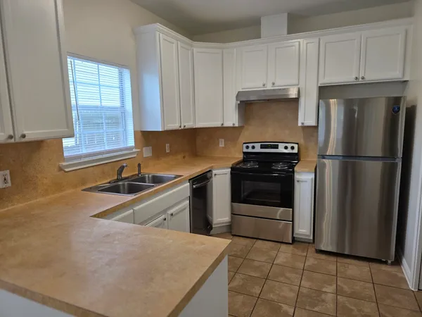 a kitchen with granite countertop a refrigerator sink and stove