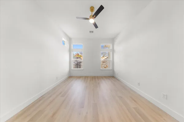 an empty room with windows and ceiling fan