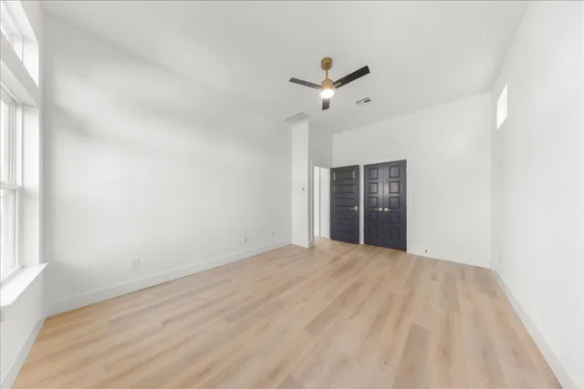 an empty room with windows and ceiling fan