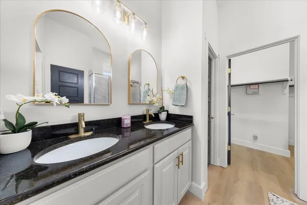 a bathroom with a granite countertop sink a mirror and shower