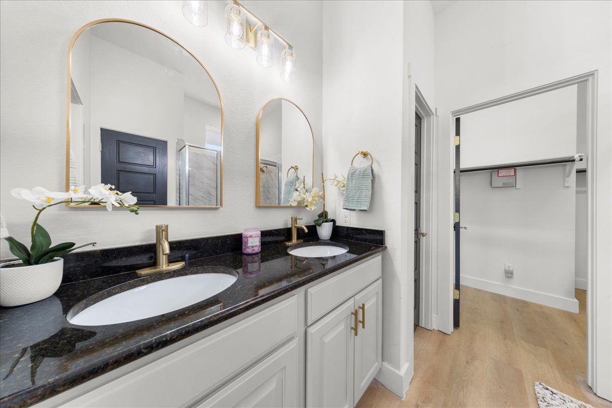 2408 Vintage Stave Road, Unit 101 Austin, TX 78748 - Photo 22 of 32 Bathroom with double vanity, a spacious closet, light wood-type flooring, and a shower with shower door