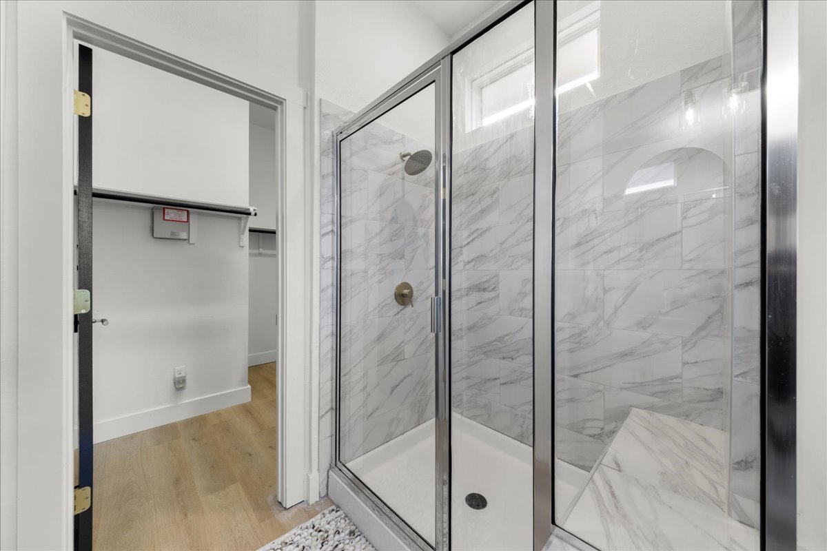 2408 Vintage Stave Road, Unit 101 Austin, TX 78748 - Photo 24 of 32 Bathroom featuring a spacious closet, a marble finish shower, and light wood-style flooring