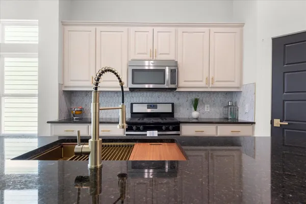 a kitchen with granite countertop a stove a sink and a microwave