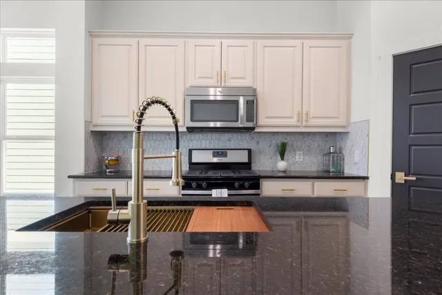 a kitchen with granite countertop a stove a sink and a microwave