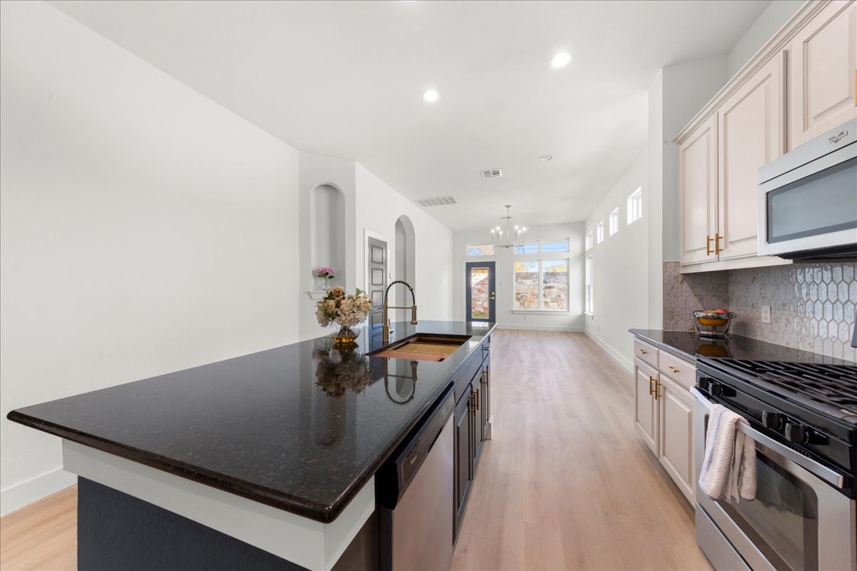 2408 Vintage Stave Road, Unit 101 Austin, TX 78748 - Photo 8 of 32 Kitchen with appliances with stainless steel finishes, dark stone counters, an island with sink, light wood-type flooring, and recessed lighting