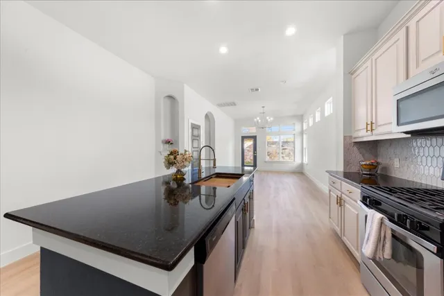 a kitchen with stainless steel appliances granite countertop a stove a sink dishwasher a refrigerator and a microwave