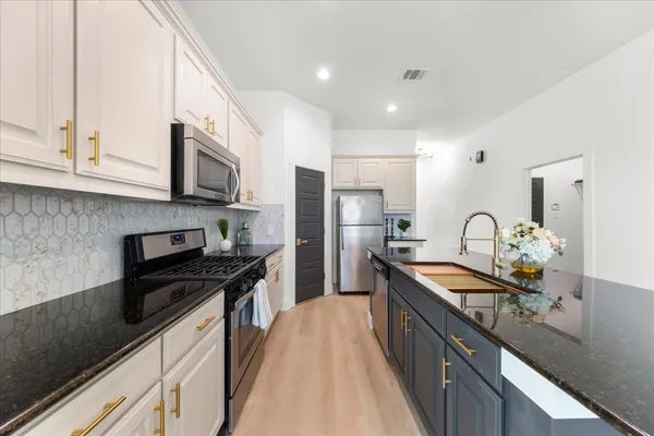 a kitchen with stainless steel appliances granite countertop a stove a sink dishwasher a refrigerator and a microwave