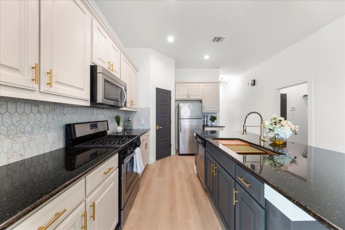 2408 Vintage Stave Road, Unit 101 Austin, TX 78748 - Photo 9 of 32 Kitchen featuring dark stone counters, stainless steel appliances, decorative backsplash, white cabinets, and recessed lighting