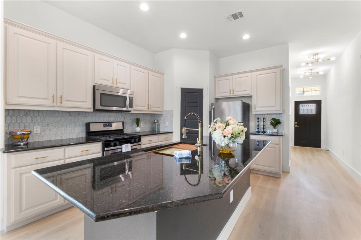 2408 Vintage Stave Road, Unit 101 Austin, TX 78748 - Photo 10 of 32 Kitchen featuring backsplash, appliances with stainless steel finishes, a center island with sink, light wood-type flooring, and recessed lighting