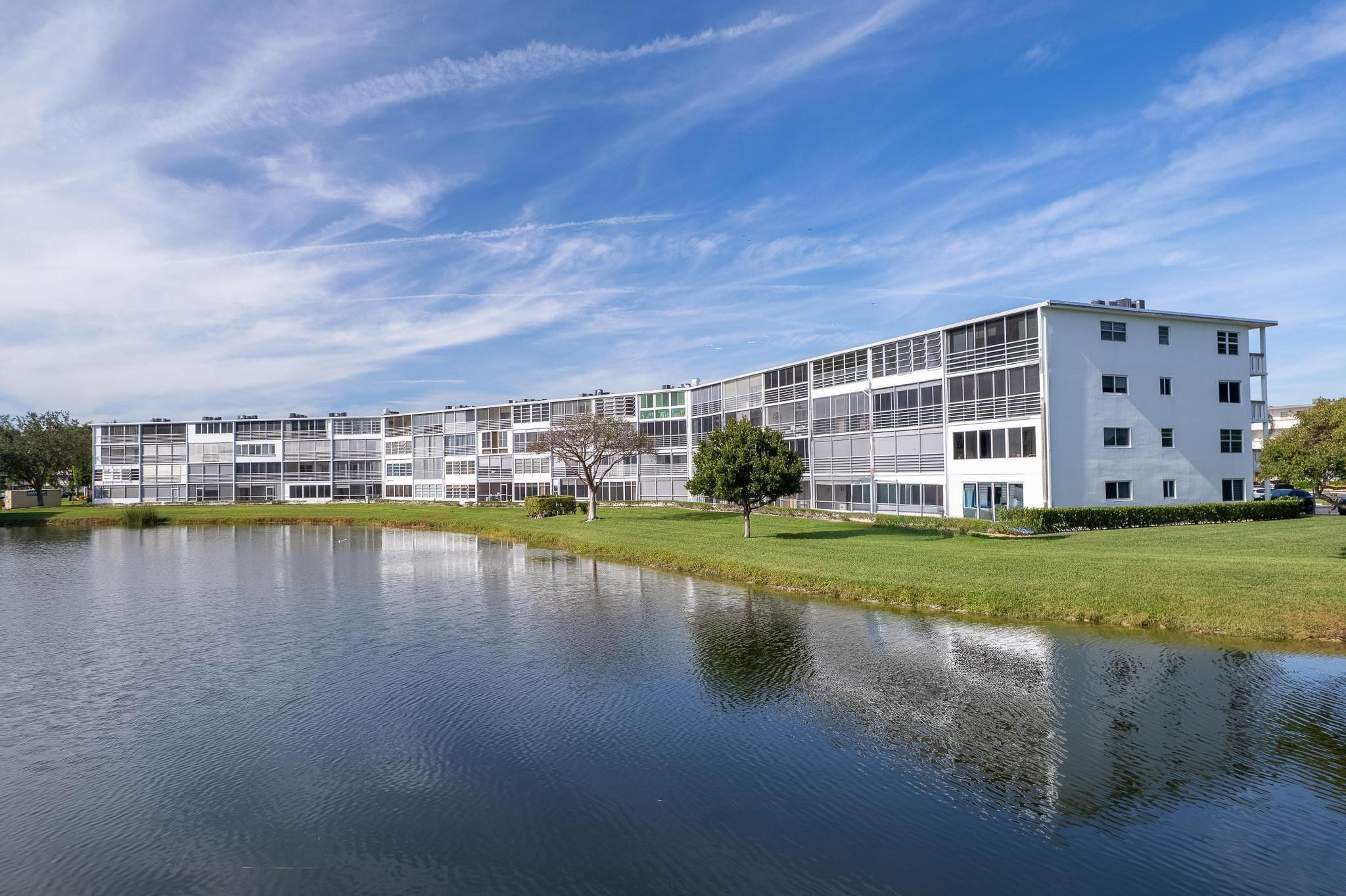 3038 Cornwall East, Unit 3038 Boca Raton, FL 33434 - Photo 25 of 32 a view of a lake with a big yard and large trees