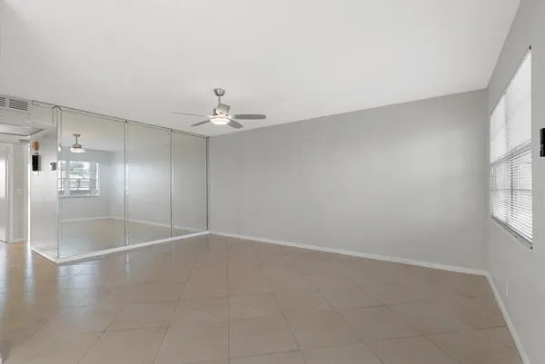 an empty room with windows and chandelier fan