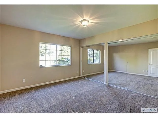 an empty room with windows and chandelier fan