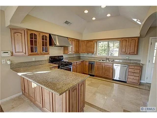 a kitchen with stainless steel appliances granite countertop a kitchen island a stove a sink dishwasher and cabinets with wooden floor