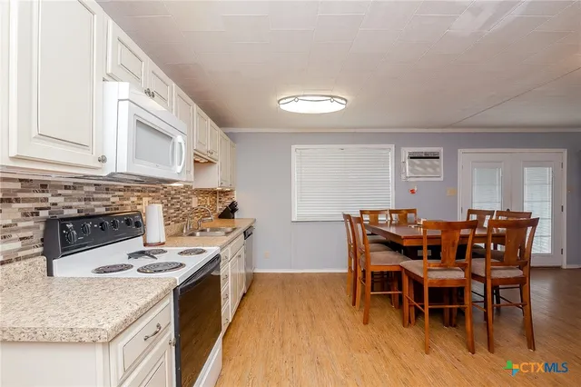 a kitchen with stainless steel appliances granite countertop a stove top oven a sink a dining table and chairs with wooden floor