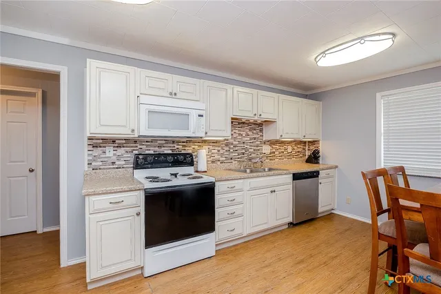 a kitchen with granite countertop white cabinets and white appliances