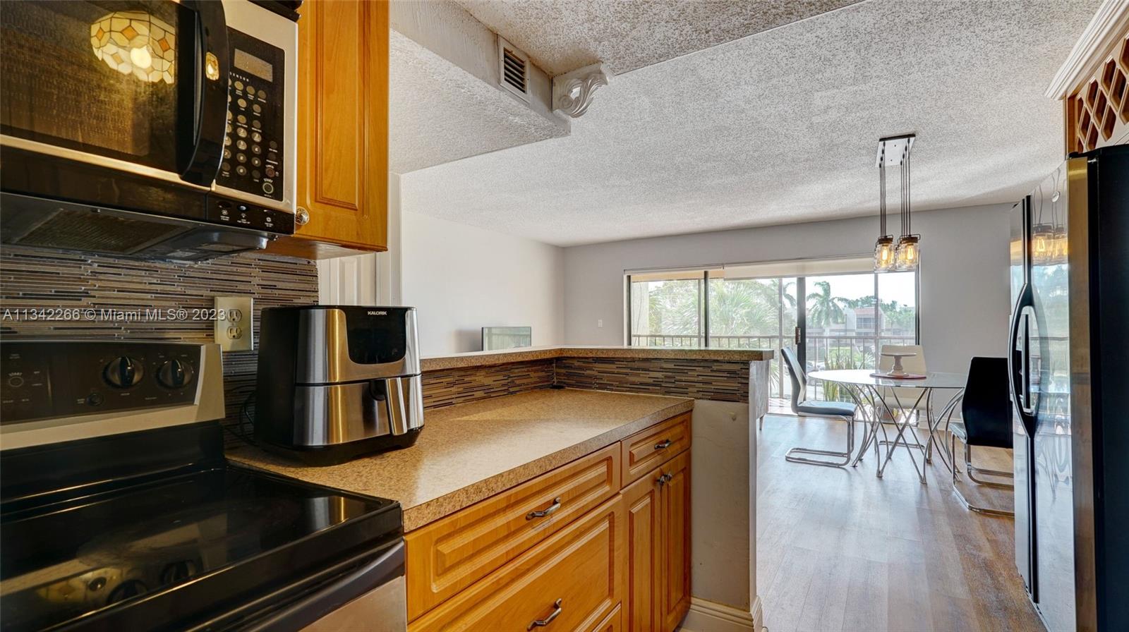 Racquet Club Apartments at Bonaventure Weston, FL 33326 - Photo 9 of 26 a kitchen with kitchen island a counter space a sink appliances and cabinets