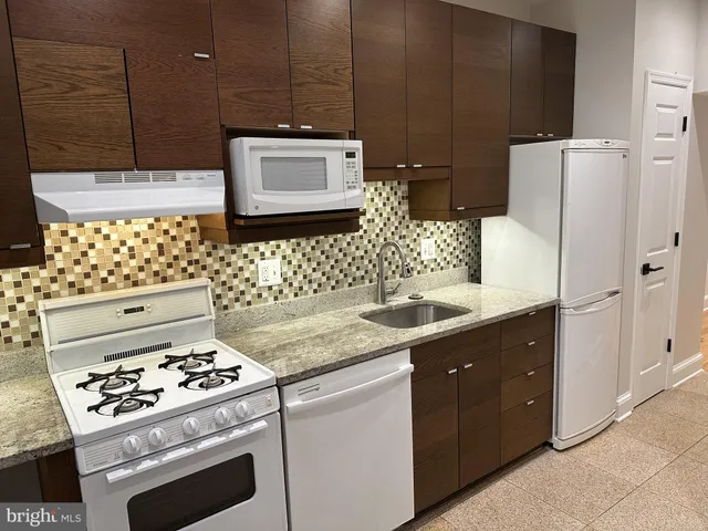 a kitchen with granite countertop a sink stove and refrigerator