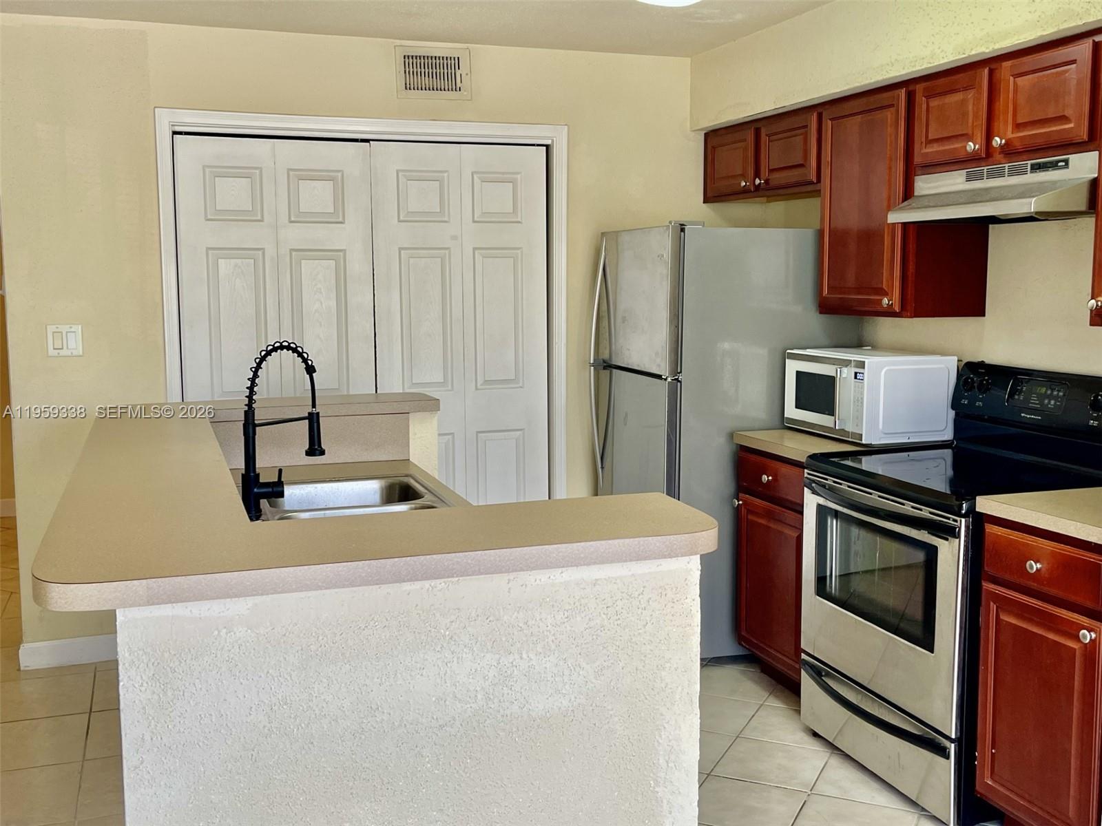 977 Riverside Drive, Unit 227 Coral Springs, FL 33071 - Photo 24 of 36 a kitchen with stainless steel appliances granite countertop a refrigerator and a stove top oven
