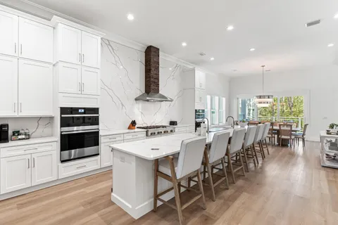 a kitchen with stainless steel appliances a stove a sink a kitchen island with a dining table and chairs