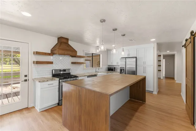 an empty room with wooden floor chandelier fan and windows
