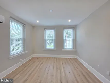 a view of an empty room with wooden floor and window