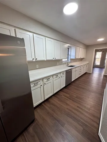 a kitchen with granite countertop white cabinets and wooden floor