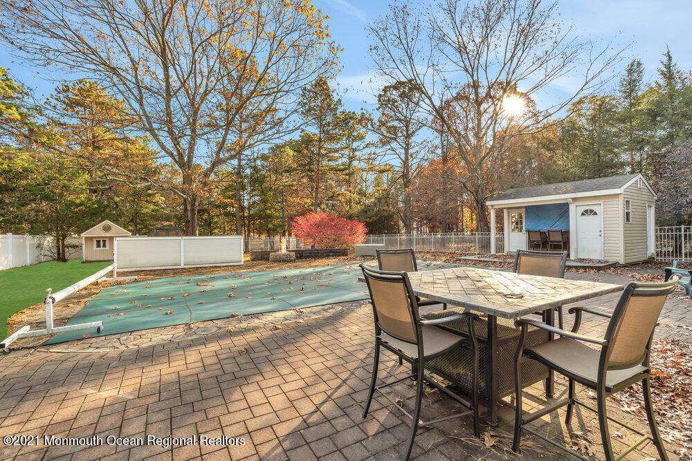 587 Reed Road Jackson, NJ 08527 - Photo 21 of 26 a view of a patio with a table and chairs and a barbeque with potted plants and large trees