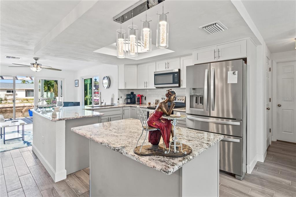 9917 San Sierra Way Port Richey, FL 34668 - Photo 13 of 33 a kitchen with stainless steel appliances granite countertop a refrigerator and a sink