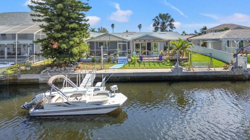 9917 San Sierra Way Port Richey, FL 34668 - Photo 33 of 33 a view of a lake with a patio and a garden