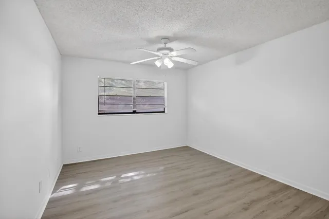 an empty room with a window and a fan