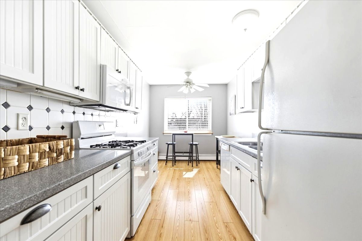 1311 South Finley Road, Unit 203 Lombard, IL 60148 - Photo 9 of 20 a kitchen with granite countertop a refrigerator a sink dishwasher and white cabinets next to a window