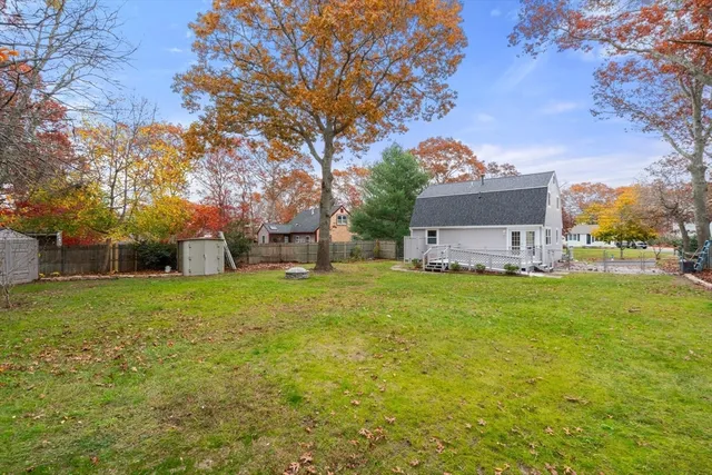 a tall yellow house with a big yard and large trees