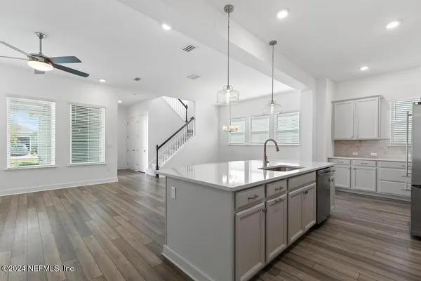 a kitchen with kitchen island granite countertop a sink appliances and wooden floor