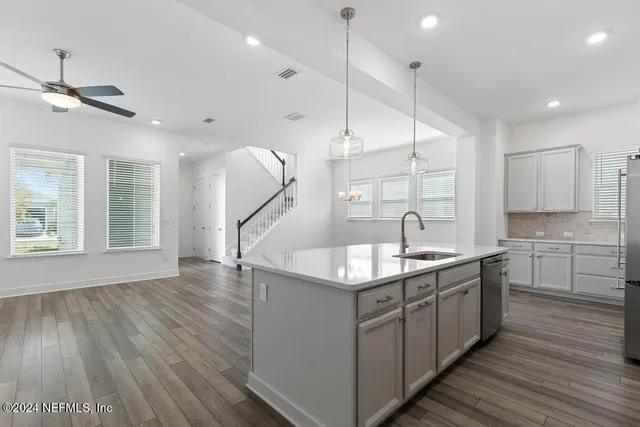a kitchen with kitchen island granite countertop a sink appliances and wooden floor
