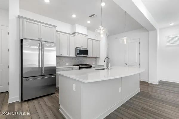 a kitchen with kitchen island granite countertop a sink cabinets and wooden floor