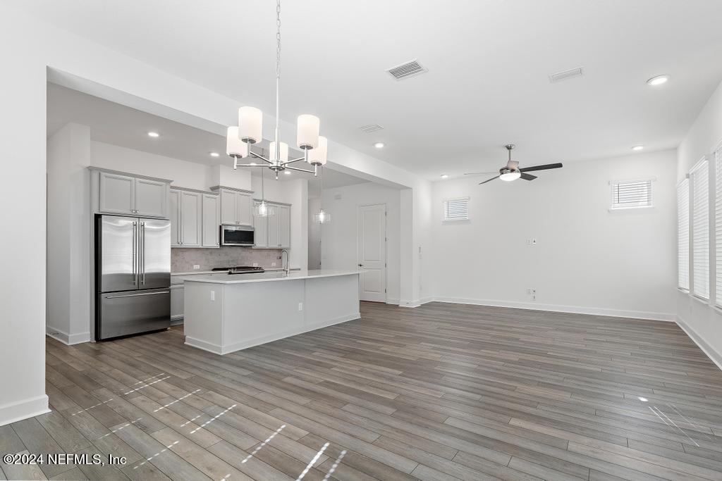 116 Alston Dr Street St. Augustine, FL 32092 - Photo 21 of 58 a large kitchen with kitchen island a refrigerator a stove a sink dishwasher a dining table and chairs with wooden floor