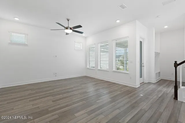 a view of empty room with wooden floor and fan