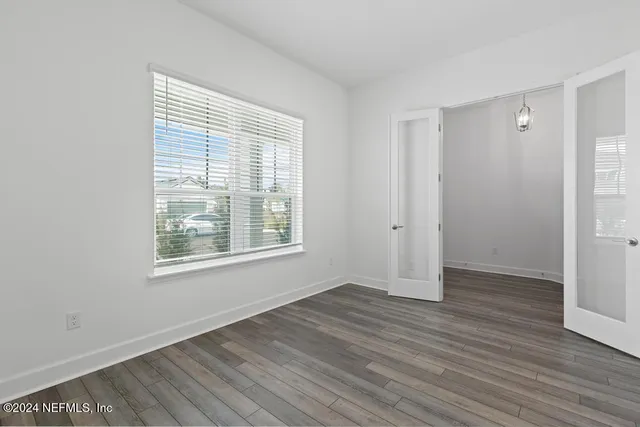 an empty room with wooden floor and windows