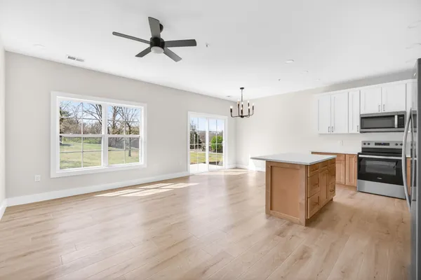 a view of kitchen with sink a microwave and cabinets