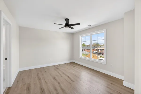 a view of empty room with wooden floor and window