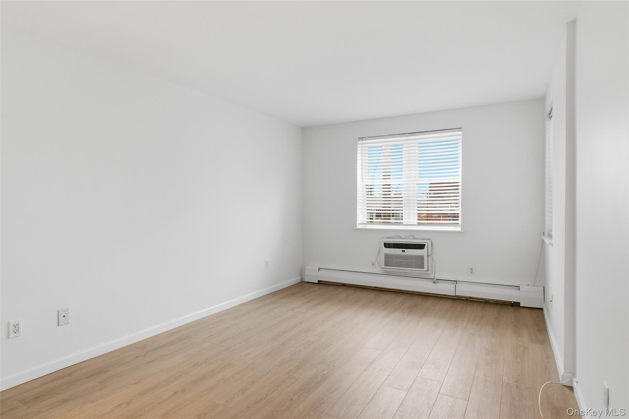 55 Monroe Boulevard, Unit 2L Long Beach, NY 11561 - Photo 18 of 25 an empty room with wooden floor and windows
