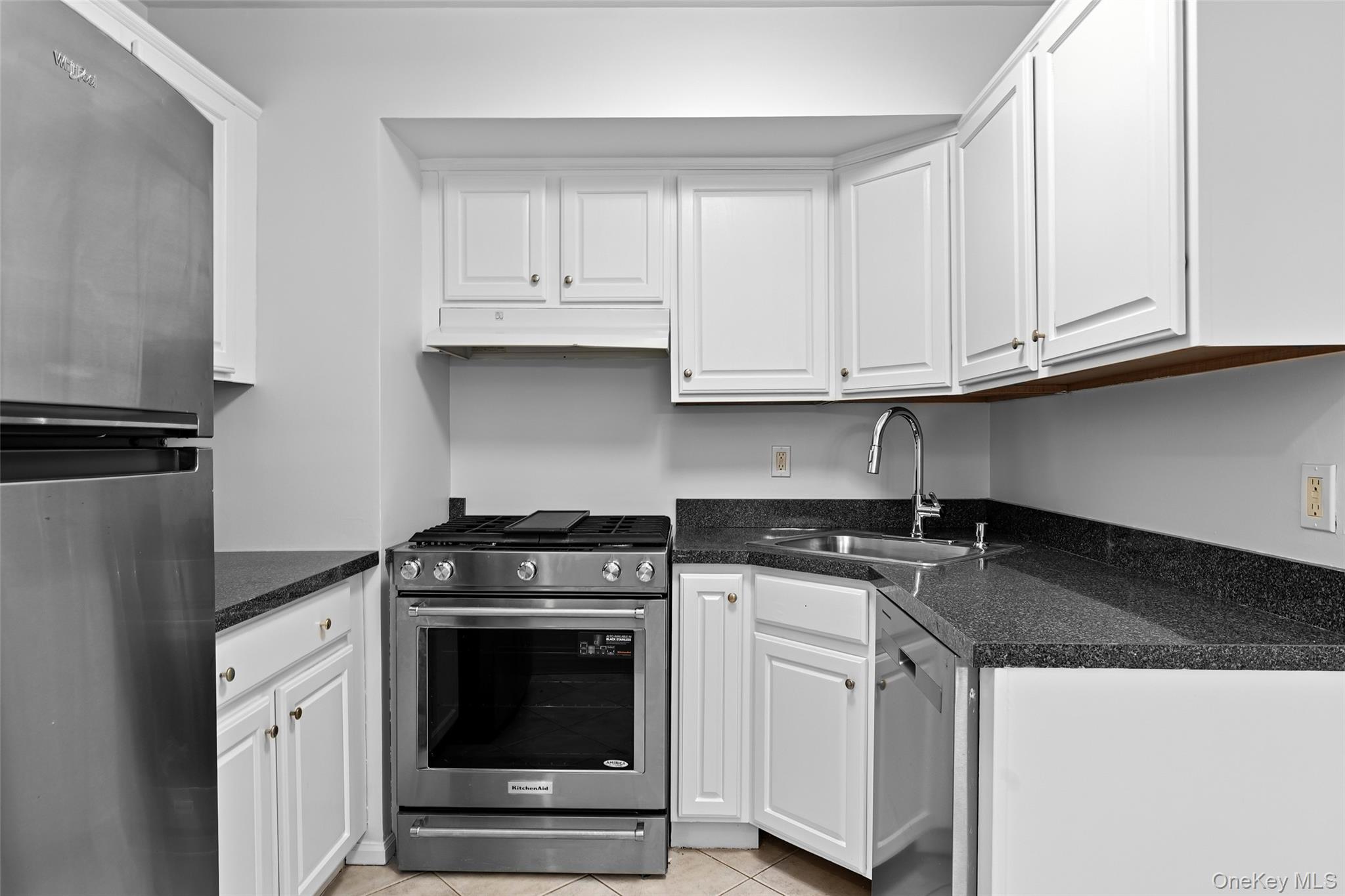 55 Monroe Boulevard, Unit 2L Long Beach, NY 11561 - Photo 2 of 25 a kitchen with granite countertop white cabinets and stainless steel appliances