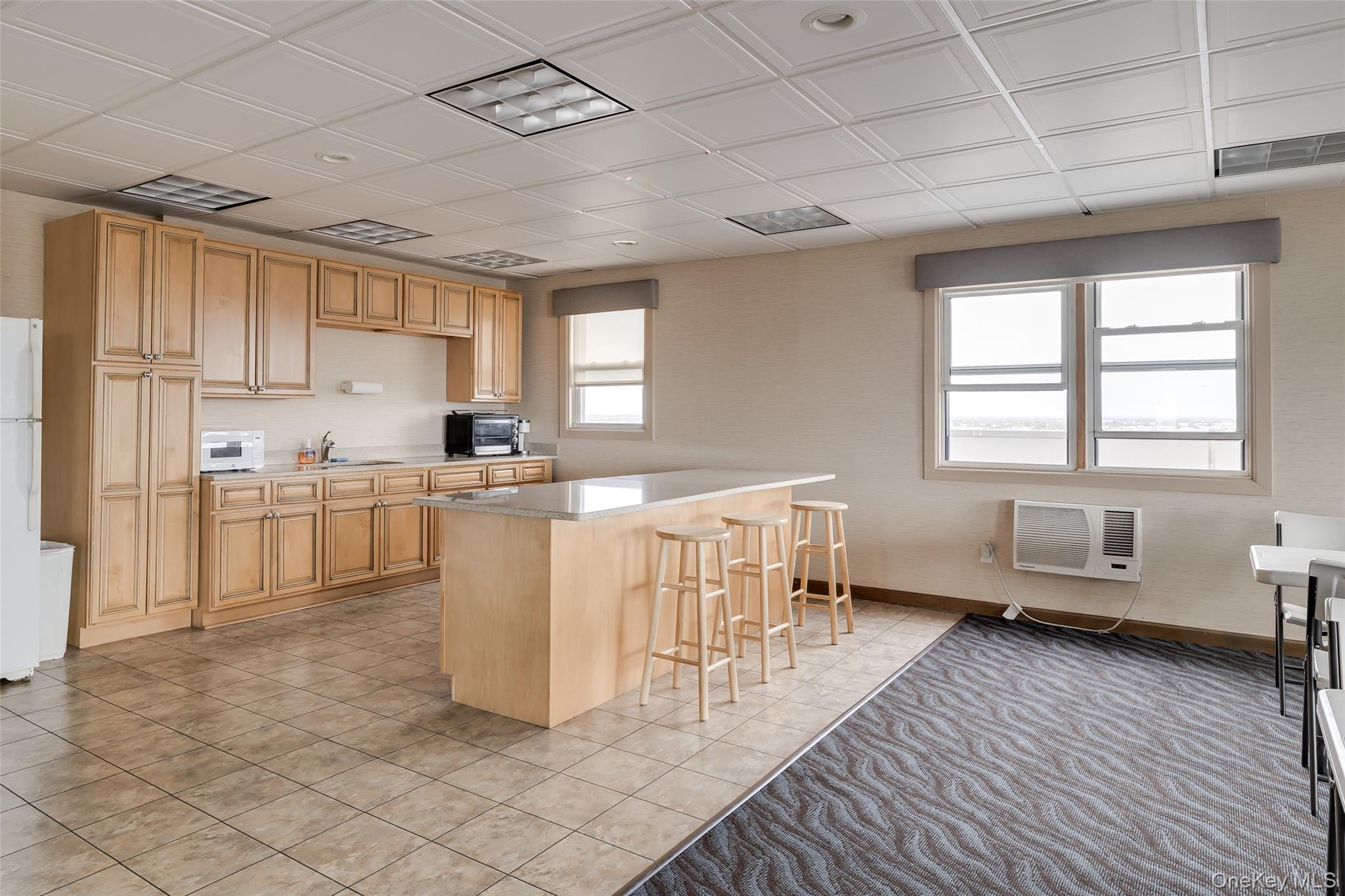 55 Monroe Boulevard, Unit 2L Long Beach, NY 11561 - Photo 21 of 25 a kitchen with a sink dishwasher a stove a refrigerator cabinets and a dining table with wooden floor