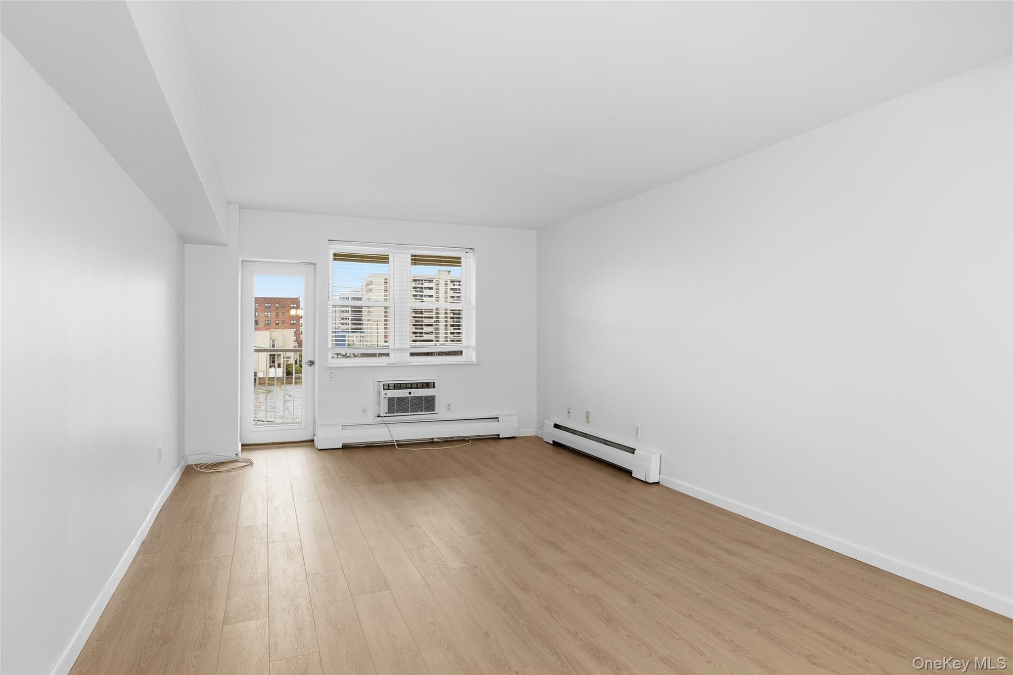 55 Monroe Boulevard, Unit 2L Long Beach, NY 11561 - Photo 5 of 25 an empty room with wooden floor and windows