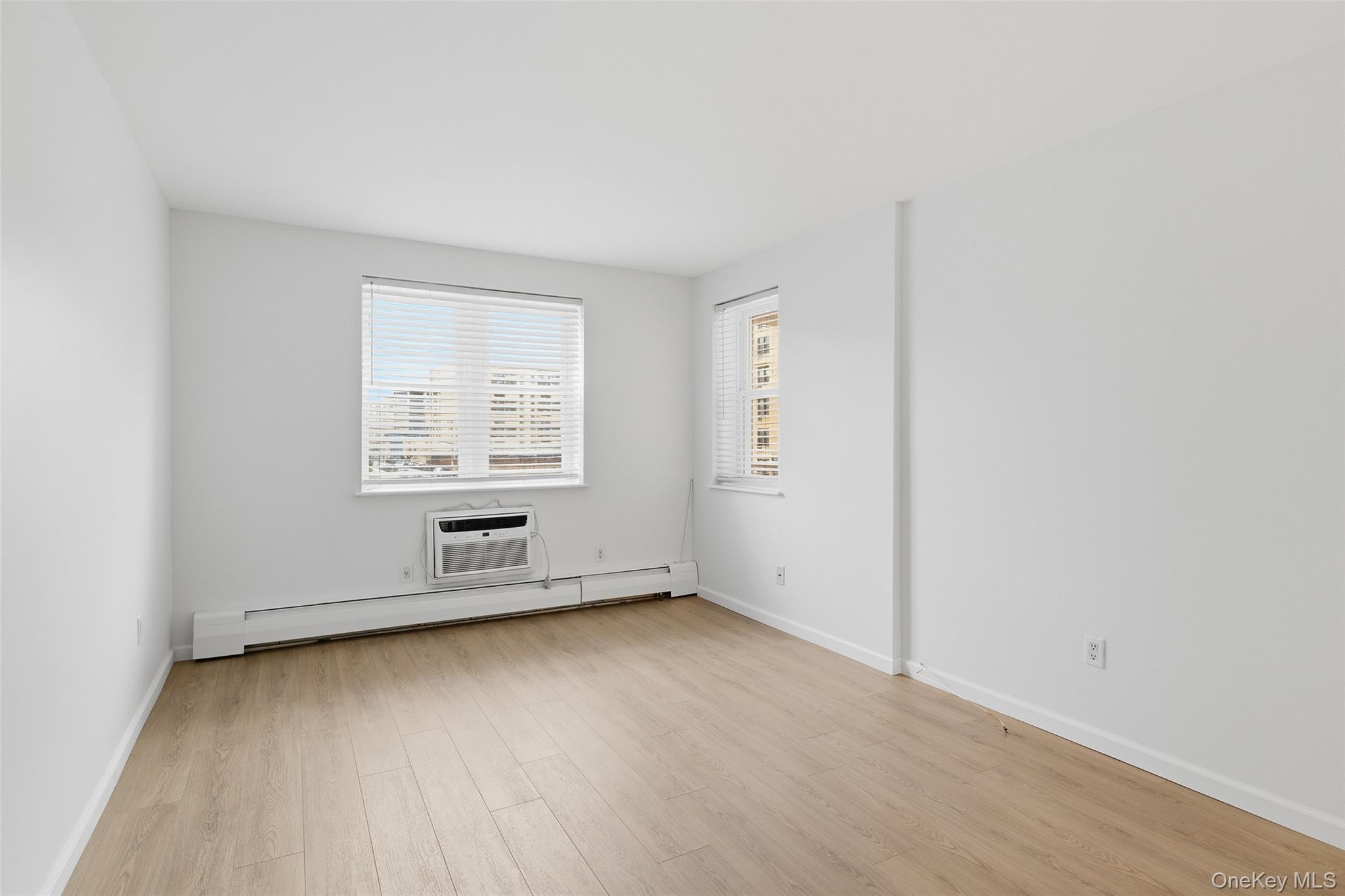 55 Monroe Boulevard, Unit 2L Long Beach, NY 11561 - Photo 7 of 25 an empty room with wooden floor and windows