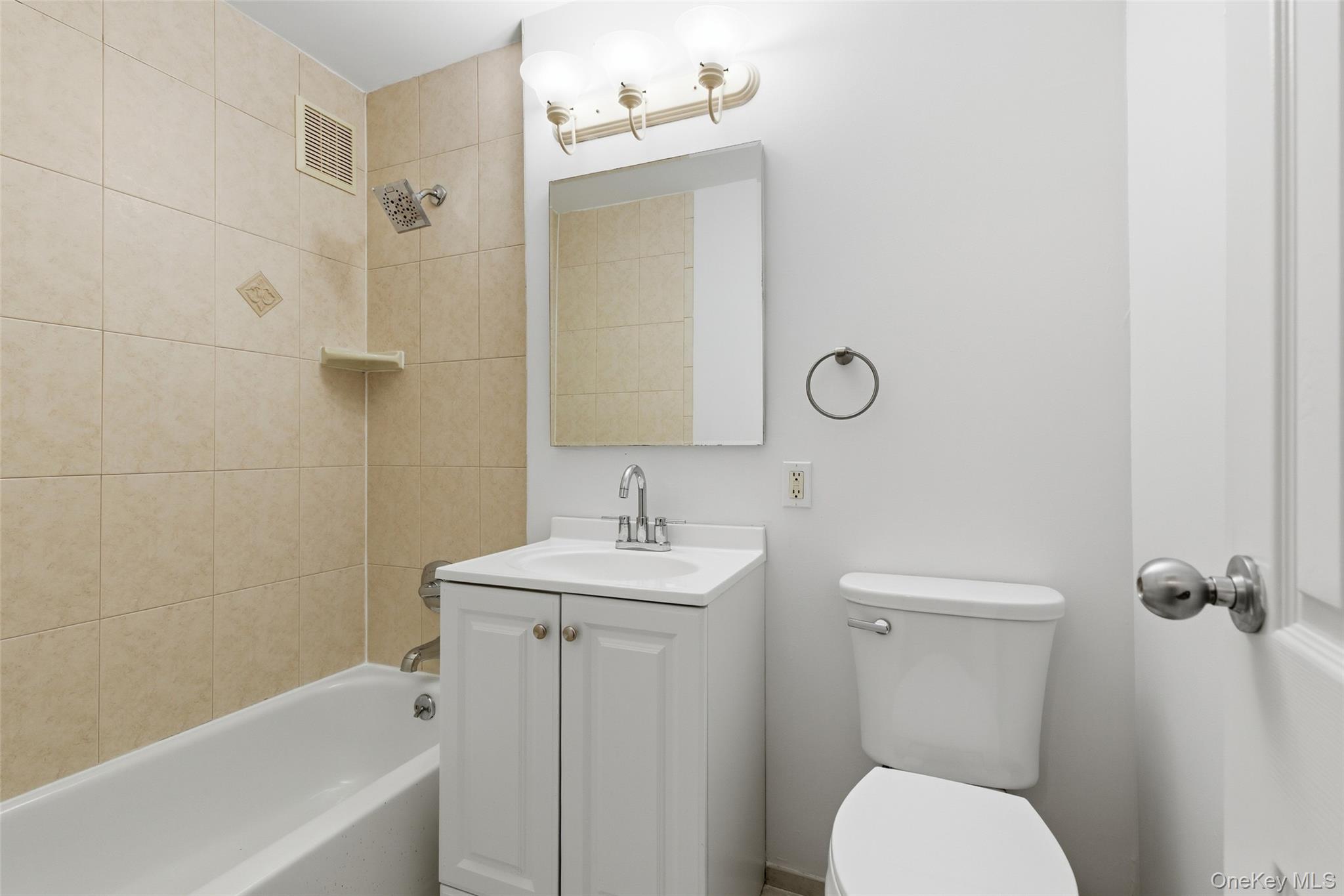 55 Monroe Boulevard, Unit 2L Long Beach, NY 11561 - Photo 8 of 25 a bathroom with a toilet a sink and mirror